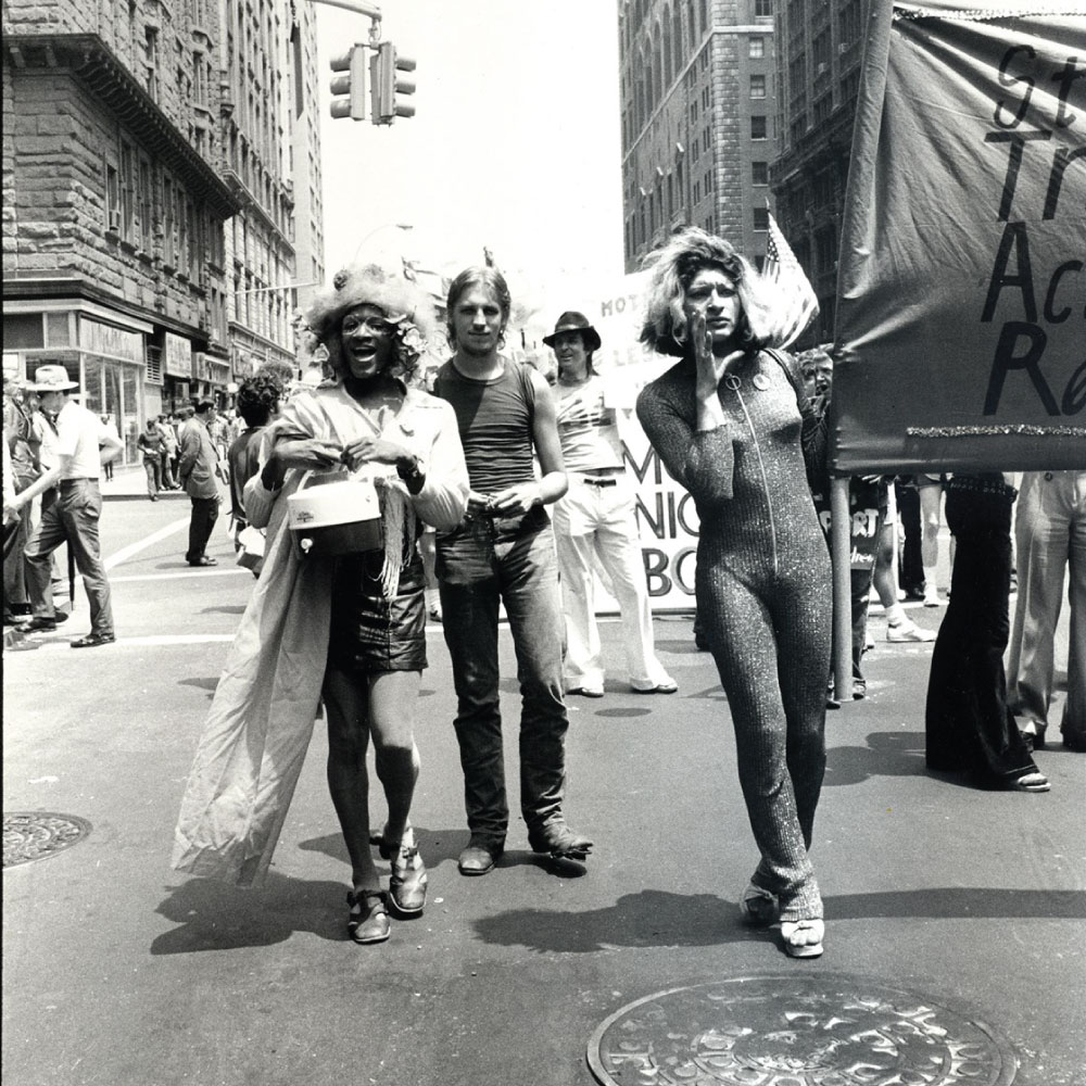 Black and white photo of three people marching in a protest.