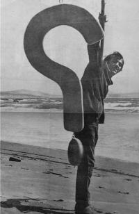 Black and white photo of William T. Wiley holding up a large question mark.