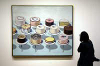 Visitor in the gallery viewing a Thiebaud painting of cakes.