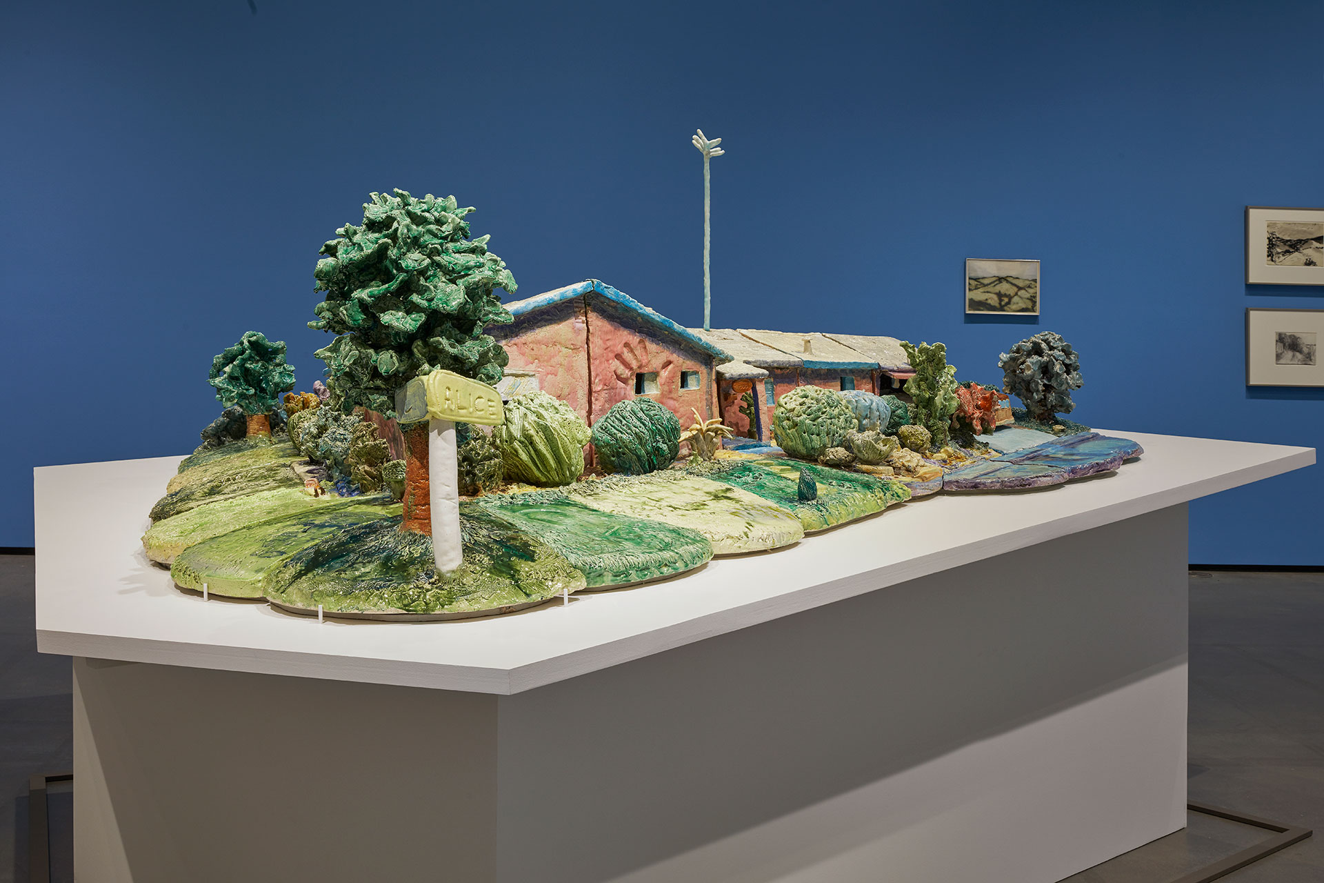 Ceramic sculpture of a house with yard and tree.