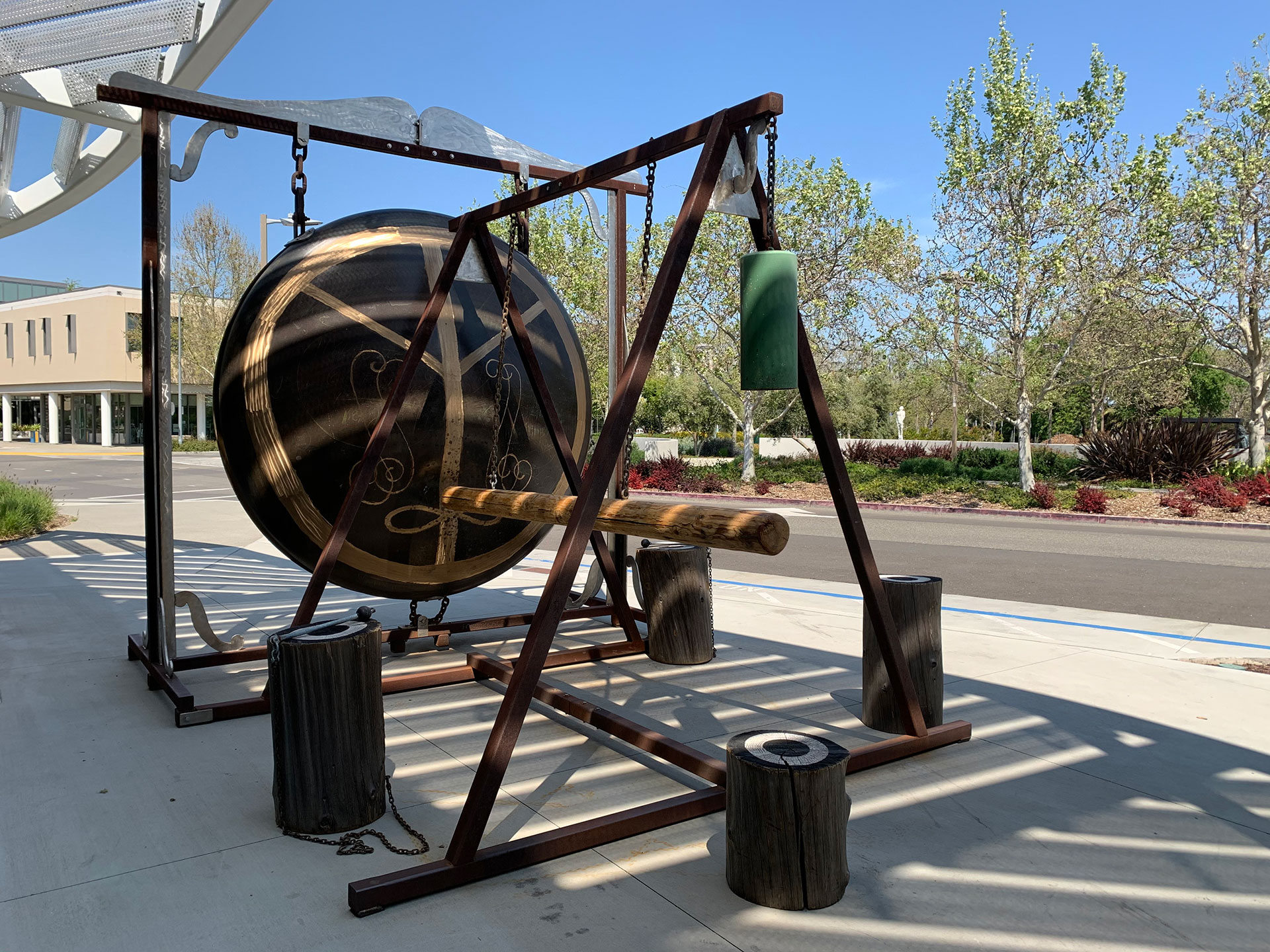 Large metal gong with log ram hanging in front of it.