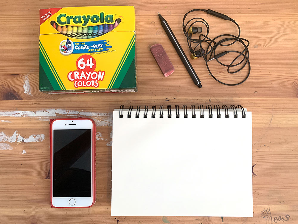 Phone, paper, crayons and headphones on wooden table.