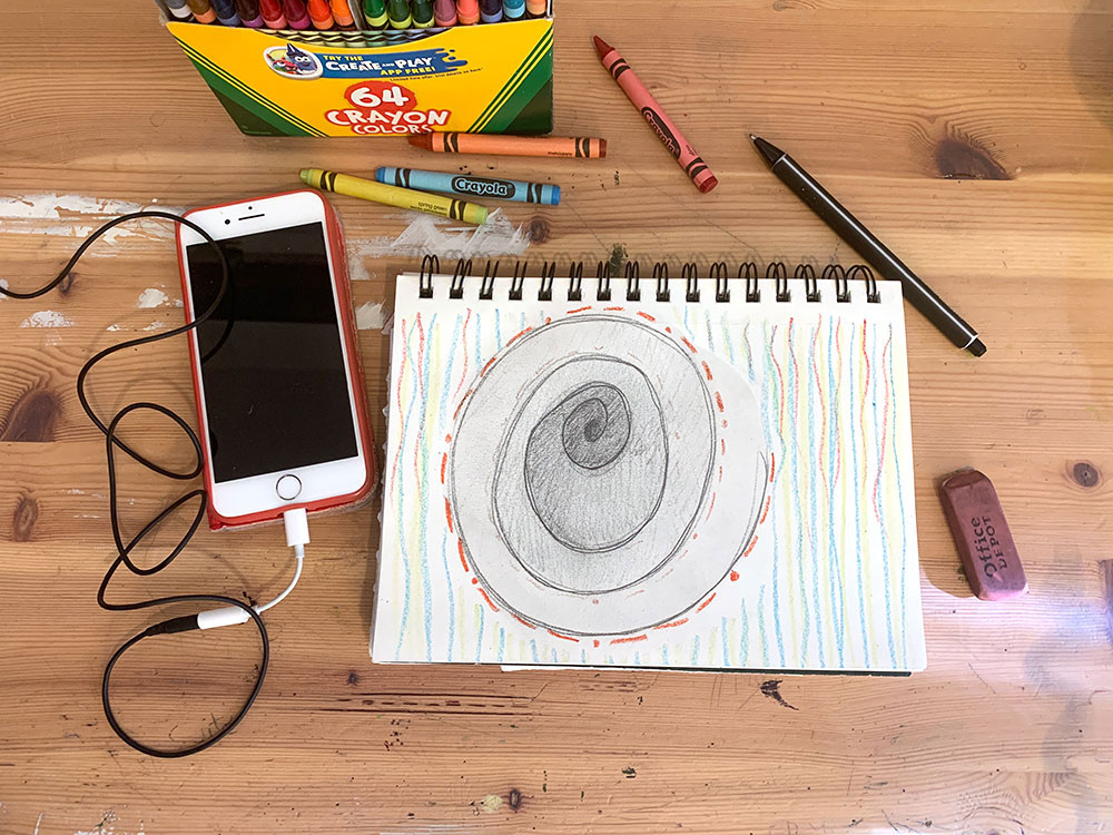 Iphone and drawing pad with grey spiral and colored lines.