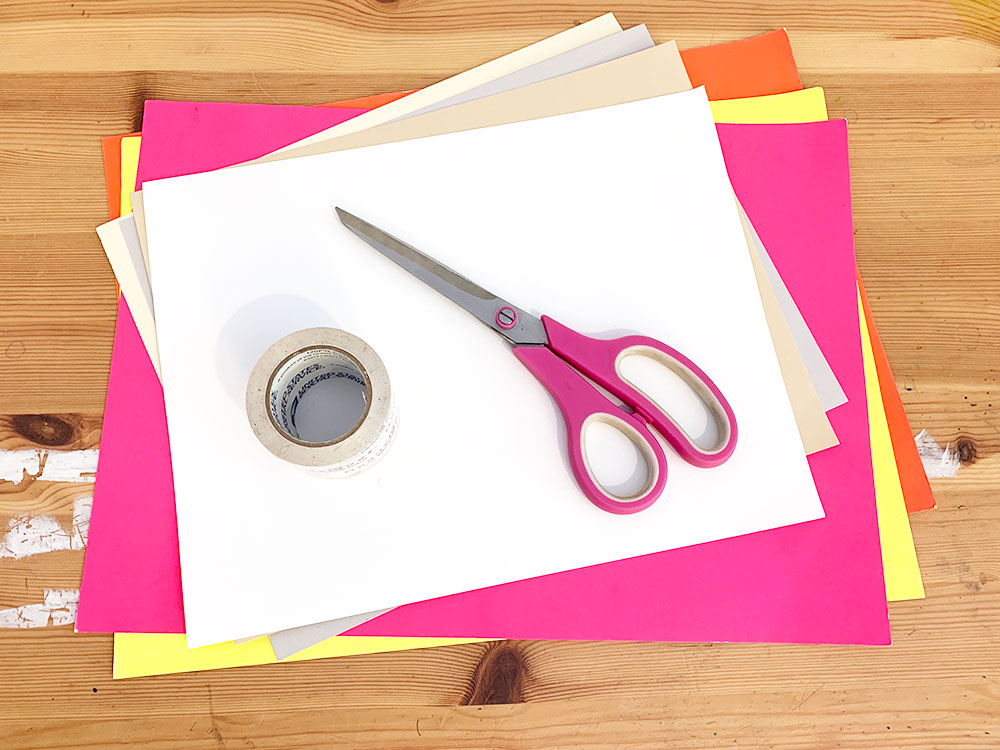 Brightly colored paper, scissors and tape on a wooden table.