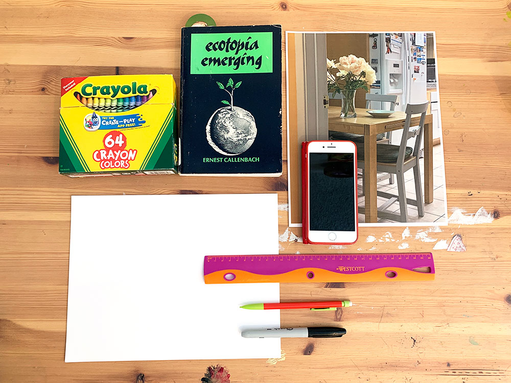 Box of crayons, book, photo, blank paper, pencils, phone, and ruler on wooden table.