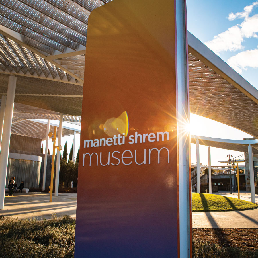 Gradient colored sign in front of a museum with the sun setting behind.