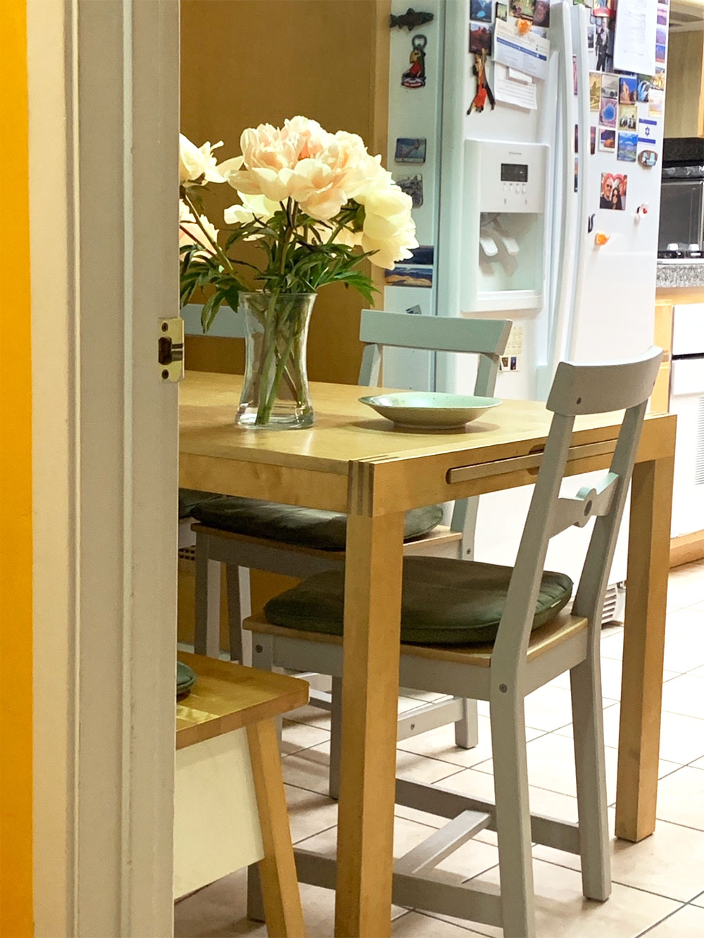 Photo print out of kitchen with table, fridge.