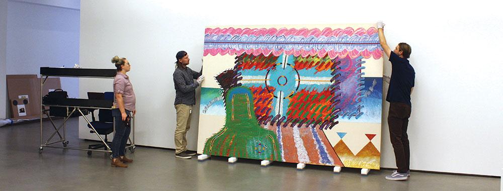 Three people installing artwork in the gallery.