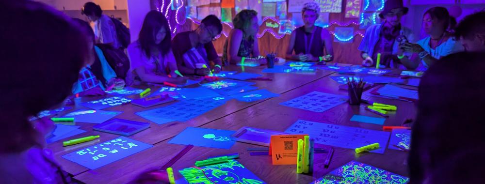 People doing art with highlighters under black lights.=