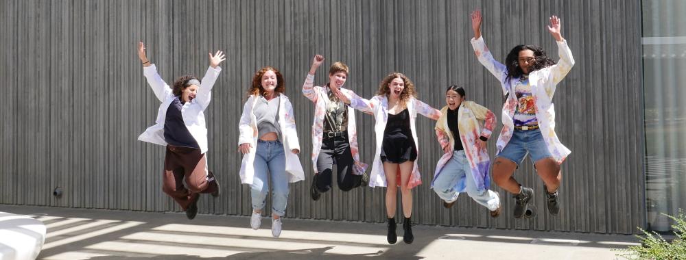 Student staff jumping in front of the museum.