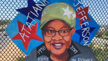 Painting of Atatiana Jefferson on cardboard and attached to a fence on an overpass.