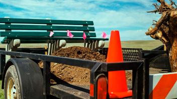 Transplant Module, 2021, 35mm film series. Utility trailer; replica of an NYC park bench; lodgepole pine roots; soil from a construction site; traffic cone; road barrier; survey flags; open prairie.