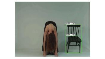 Screen shot of performance by Avital Meshi showing person bent over next to a wooden chair.