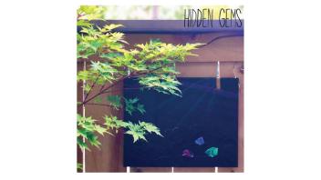 Painting by Joseph Vasinda hanging outside with the words 'Hidden Gems' at the top.