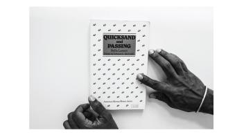 Black and white photo of hands holding a book titled 'Quicksand and Passing' by Nella Larsen.