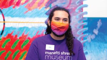 Student wearing a purple museum shirt in front of a painting in the gallery.
