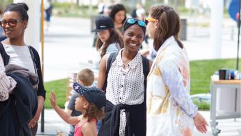 Student talking with a museum visitor on the event plaza.