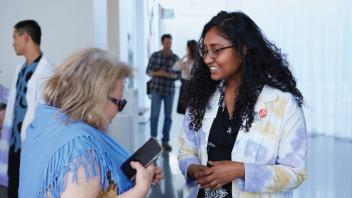 Student talking with museum visitor. 