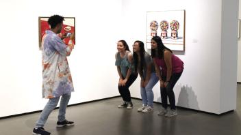 Visitor Services student taking a picture of three visitors in the galleries.