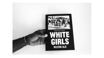 Black and white photo of a hand holding a book titled 'White Girls' by Hilton Als.