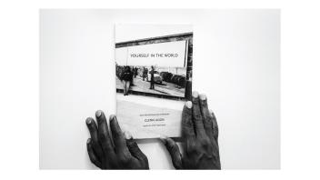 Black and white photo of hands holding a book titled 'Yourself in the World' by Glenn Ligon