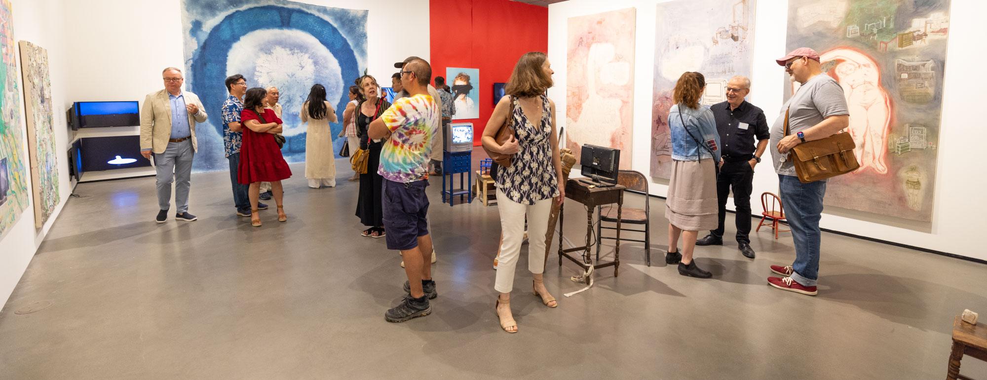 People looking at art and talking in the galleries during the 2024 grad show.