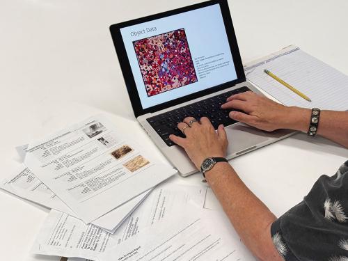 Person typing on a laptop with paper notes next them.