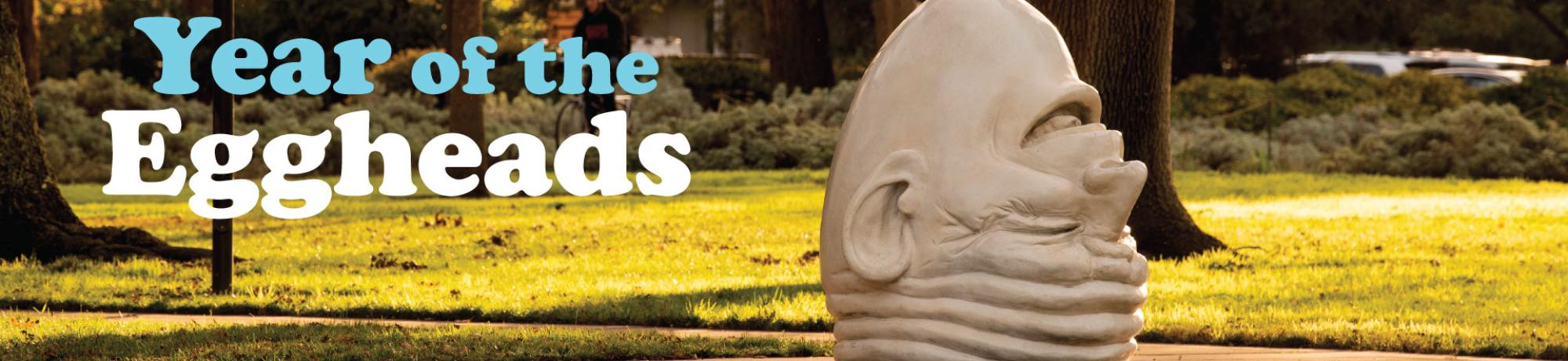 Upside down laughing egghead sculpture on campus and text overlay reading 'Year of the Eggheads'.