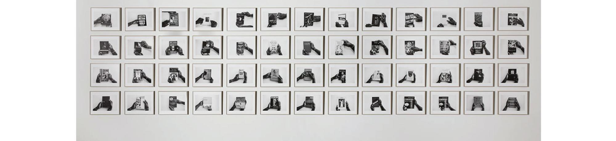 Installation photo of Kemp's Possible Bibliography art featuring 52 black and white photos.