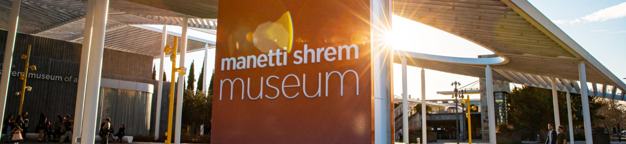 The museum sign and plaza with the sun setting behind it.
