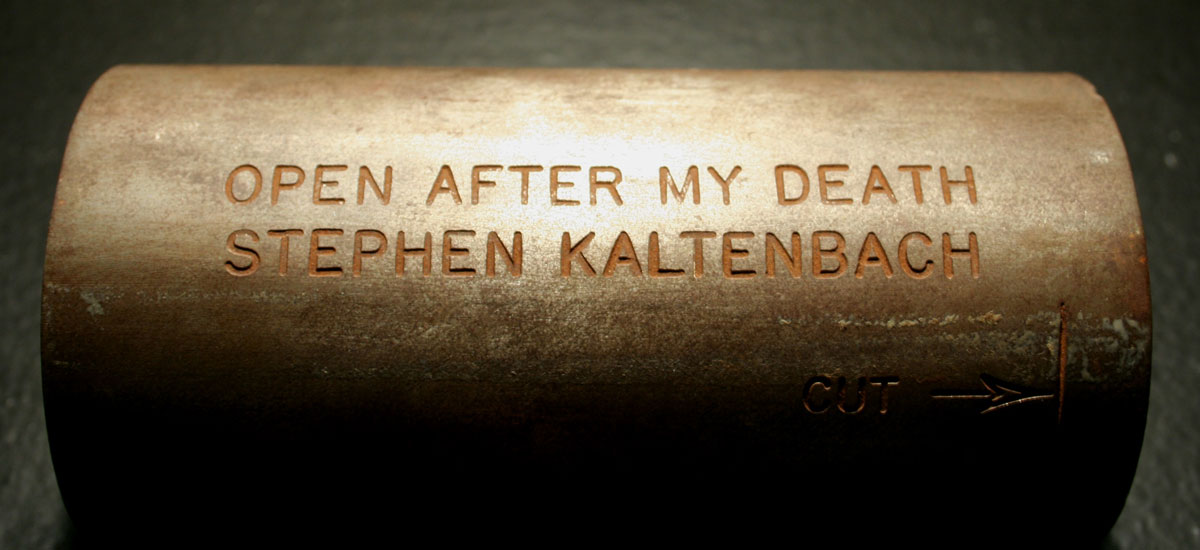 Photo of brass colored metal tube with words inscribed 'Open after my death, Stephen Kaltenbach'