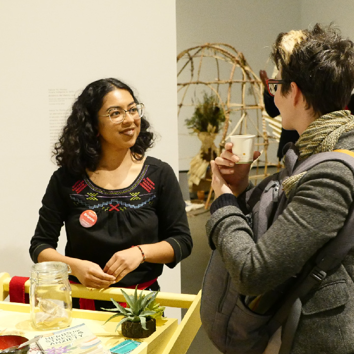 Student and visitor learning about tea blends at the Botanica del Barrio cart at the Museum.