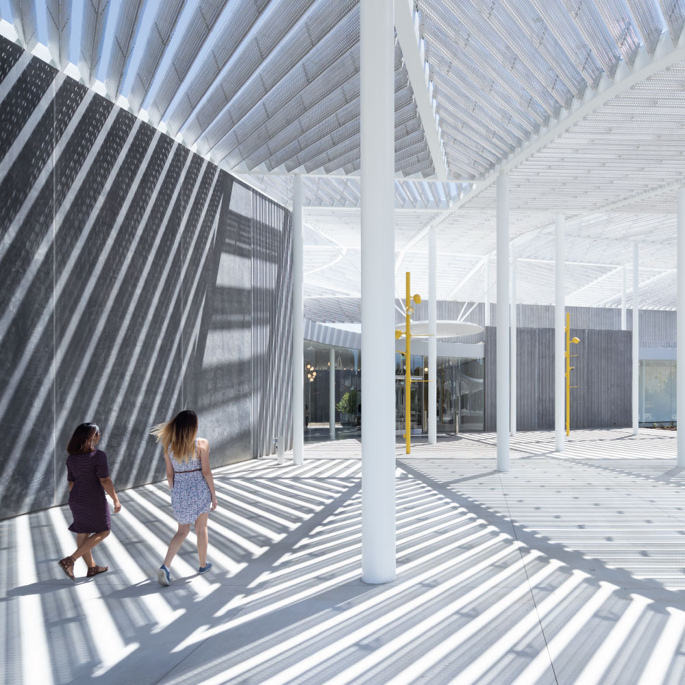 Two girls walking on the event plaza in front of the museum on a sunny day.