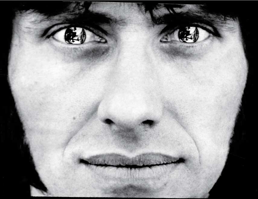 Black and white photo of man's face with mirrored contacts in the eyes.