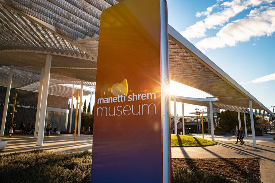 Museum sign in front of the plaza canopy on a sunny day.